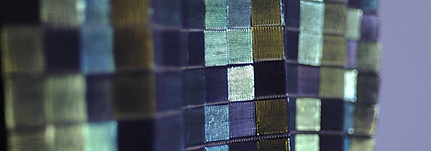 woven wire artwork in varied blues: from blue-silver to turquoise and navy, shown on the side - light filters off each square