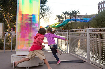 example of Context & Community Engagement by artelier public art curators commissioning a piece by chris wood next to a river in the event with kids running around it 
