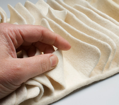touching felt by kristy kún in a wave like motion of creams and whites featuring a hand caressing it up closejpg