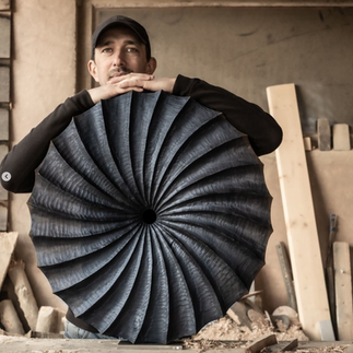 The artist standing in front of his carved wood sculpture commissioned by Artelier art consultancy