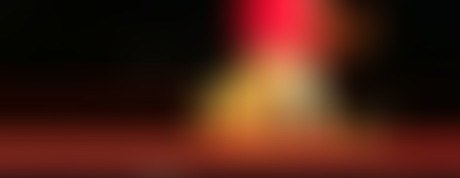 © Courtesy of North east statues showing a night lit photo of a large brightly lit sculpture showing a big red neon bucket pouring out artificial waves of yellow neon molten