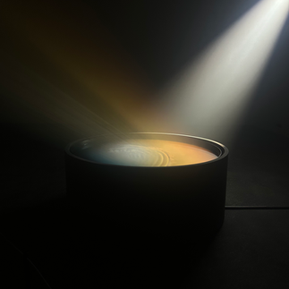 Boris Acket’s Sunbeam, Captured (2023) is a light installation that recreates a ray of sunlight reflecting off a body of water for 15 minutes. Inspired by the ephemeral beauty of everyday life, the work attempts to capture a fleeting moment by reproducing Acket’s personal observation of a rain puddle reflecting a sunbeam.  In a darkened room, visitors watch white light strike a shallow layer of water, which refracts colored beams in a dynamic light play. Under the basin sits a mirror designed by Dutch artist Sabine Marcelis (b. 1985) that enhances this interaction, reflecting warm to cool hues along the Kelvin color temperature scale. A system of linear actuators generates gentle waves in the pool.  As the artwork’s multipoint lights mimic the sun’s daily journey, visitors are invited into this perpetual pocket of time to observe transient sunlight and contemplate finding joy in the mundane.