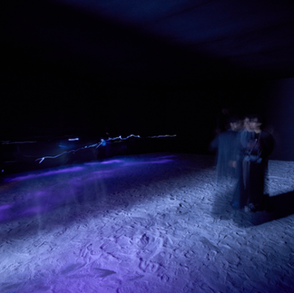 Ayman Yossri Daydban’s White Noise (2016) is an interactive sensory art installation that invites the viewer to explore their inner world through the act of walking on salt. Designed to enhance self-awareness, the artwork is part of Daydban’s The State series, which encourages the audience to discover a ‘state’ within each space.  Visitors enter a darkened room where the floor is covered with nearly two tons of natural salt. The darkness, sounds and textures of the space evoke a time before the cacophony of modern life, when humans were more connected to nature and raw materials. A neon sign beams on the other end, bathing the surrounding space in a soft glow. The sign asks: “When was the last time you heard the crunch of your shoes walking on salt?”  Reflecting on these words, visitors are encouraged to tread on the grains, either barefoot or with their shoes on, and contemplate how they interact with their surroundings.