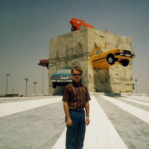 Contemporary public art installation featuring the portrait of a young child and a cemented block binding several colourful vintage cars in the background